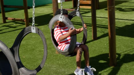 side view of african american schoolboy playing on a swing in school playground 4k