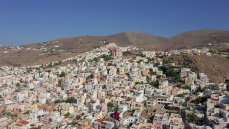 slow drone reveal shot of ermoupoli city in syros island, greece during sunrise