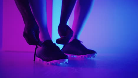 Close-up-of-black-african-male-soccer-player-tying-shoelace-on-studio-slow-motion.-Footballer-tying-his-shoe.-Low-section.-tying-football-boots-preparing-for-a-football-soccer-match