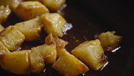 vista de primer plano dados de papas fritas en una sartén, cuchara de madera revolviendo en una sartén