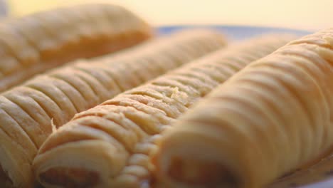 close up details of sausage rolls on plate after baking. delicious traditional english fresh bakery product. british snack cuisine. pork meat wrapped in puff pastry.