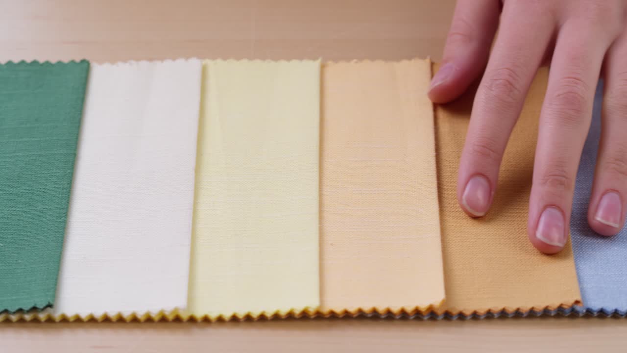 Hand Touching and Comparing Colorful Fabric Swatches