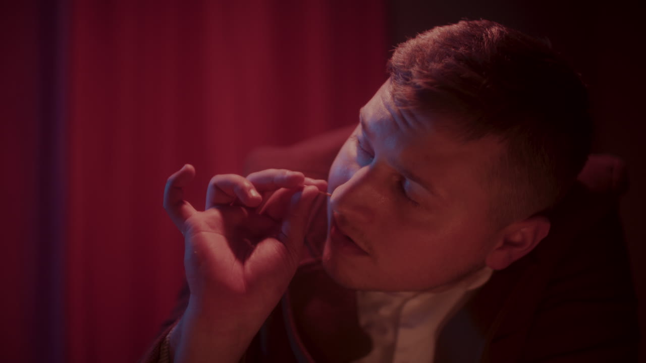 Man Taking a Pill in a Dark Room