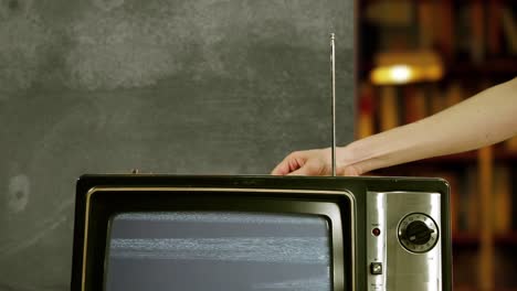 man hand adjusting the antenna of an old television with blue screen. 4k.