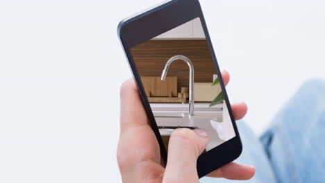 persona que sostiene un teléfono inteligente con interiores de cocina modernos mostrados en la pantalla