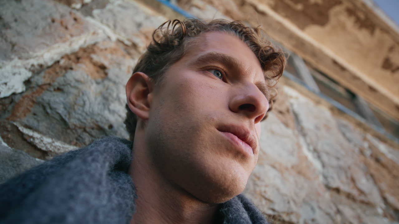 Frustrated guy considering problems leaning old building wall closeup. Sad man