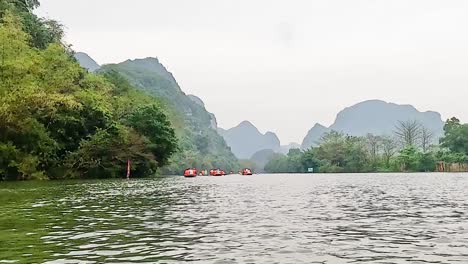 tranquil river scene with green hills and distant mountains under a cloudy sky.