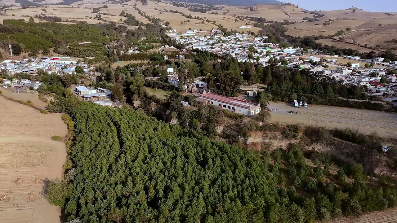 Panoraamanäkymä Ex Hacienda San Jacinto Ixtolucan yltä, kallistus ylös Pico de Orizaba -tulivuorelle. Pieni meksikolainen kaupunki vihreän metsän ympäröimänä, taustalla majesteettinen tulivuori.