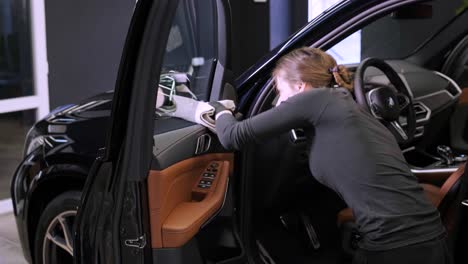 el lavador de coches profesional con guantes negros limpia el coche después de lavar y forrar la cerámica. conceptos de: trabajo profesional, varias herramientas de lavado, limpieza para brillar.