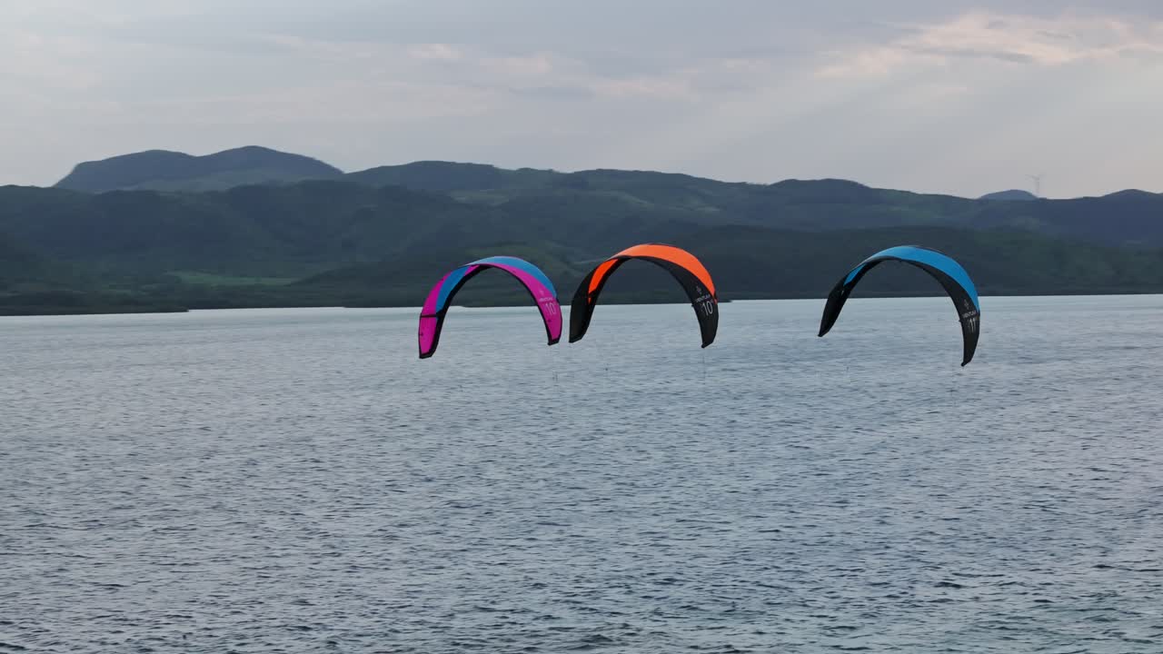 배경 에 산 들 이 있는 조용 한 바다 에서 카이트보딩 을 하는 것