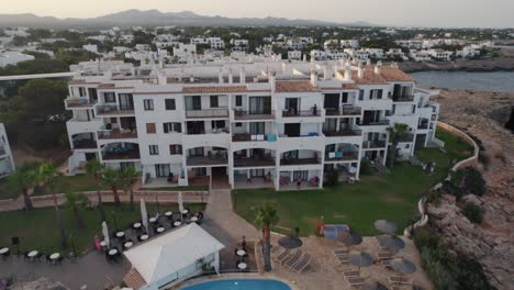 aerial shot of a hotel villa in 7 rocas, mallora, spain besides the beach during sunset