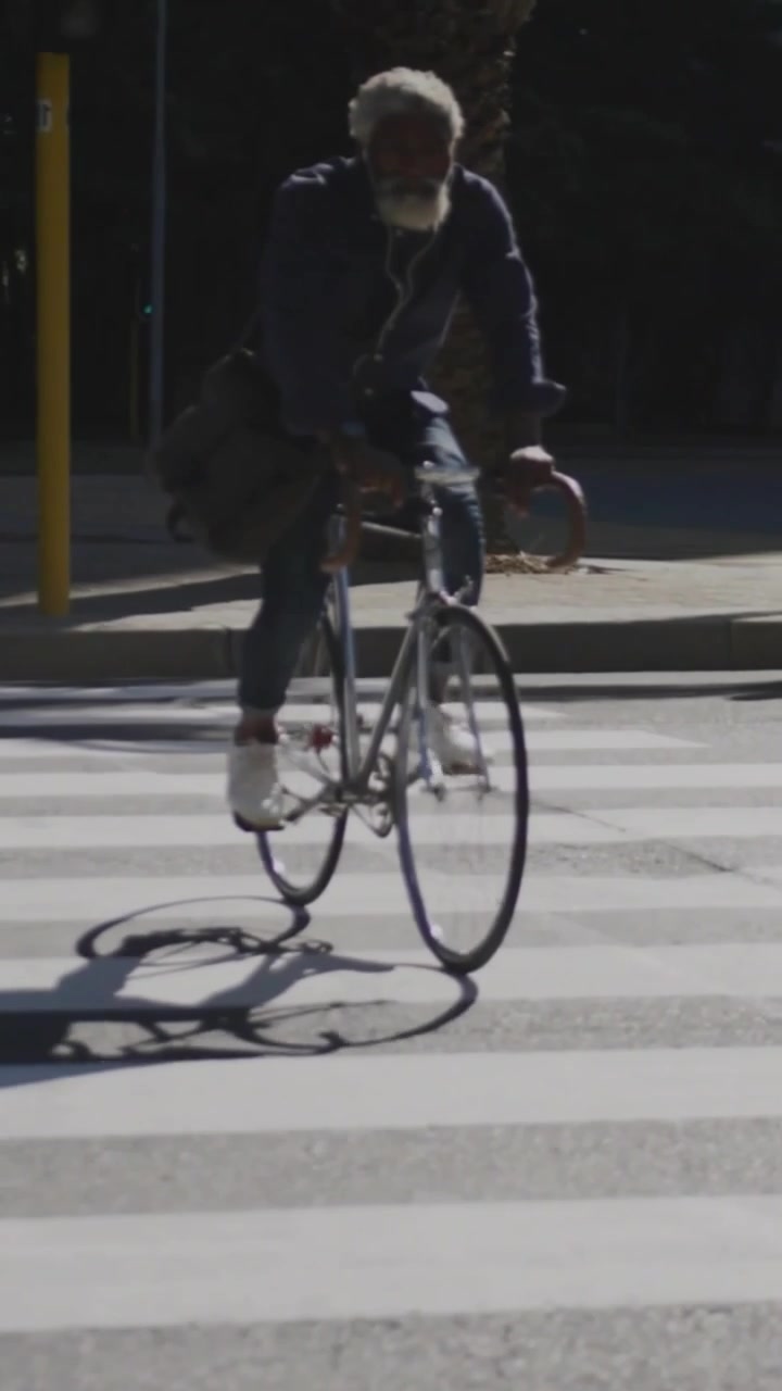 Vertical video: Male cyclist commuting across crossing, nearing camera, causing chart overlays