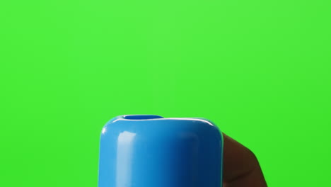 close-up of a blue plastic container top against a green screen background