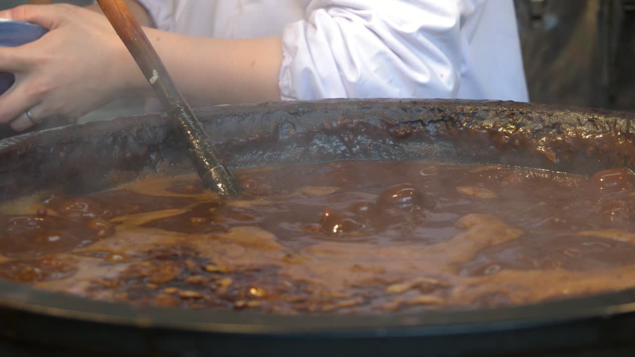 Uno chef in uniforme bianca mescola una pentola che bolle di tradizionale stufato di manzo al miso giapponese.