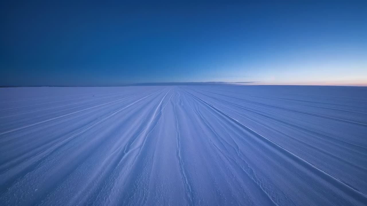 Moving forward forward-facing camera traversing groomed snow toward horizon at dawn, showing ridges
