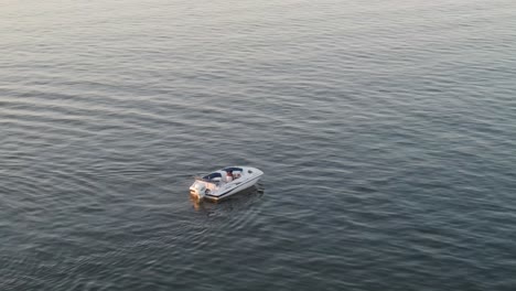 Barco-De-Motor-Aislado-En-Medio-Del-Océano-Azul-Durante-La-Puesta-De-Sol