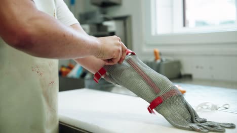 Butcher-Preparing-Left-Hand-With-Protective-Vinyl-Glove-Before-Putting-On-Wire-Metal-Glove