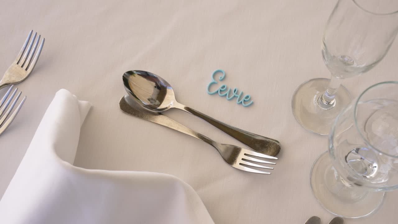 A beautifully arranged dining table showcases sparkling glassware, polished cutlery, and a personalized name card, creating a warm atmosphere for a joyful event