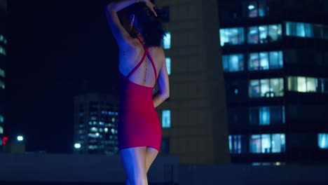 With-the-Caribbean-city-lights-of-Port-of-Spain,-Trinidad-in-the-background,-a-Hispanic-girl-stands-on-a-rooftop