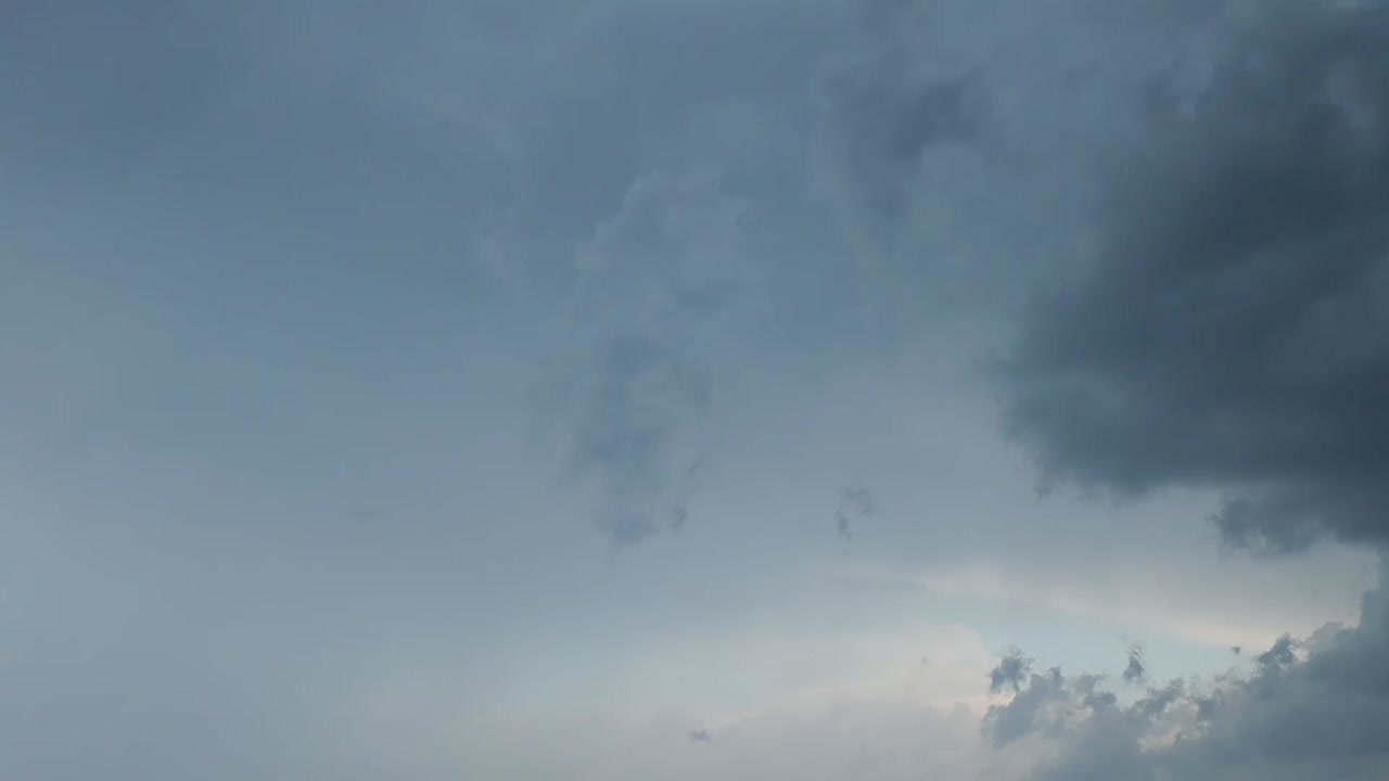Dramatic dark storm clouds fill the sky, creating a moody, overcast atmosphere with varying shades of gray and subtle light breaking through