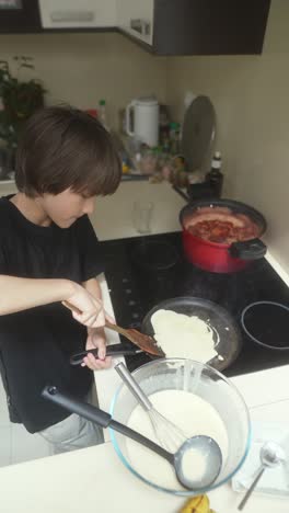 a young boy cooking pancakes