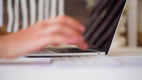 Woman-types-information-on-modern-laptop-at-white-table