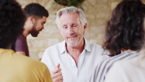 Senior-man-gesturing-while-talking-to-his-friends-at-a-table-in-a-restaurant,-close-up