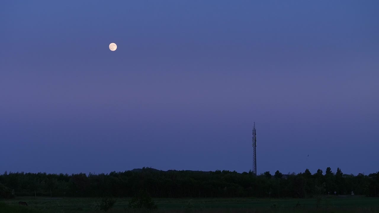 полная луна на вечернем голубом небе над силуэтом пейзажа