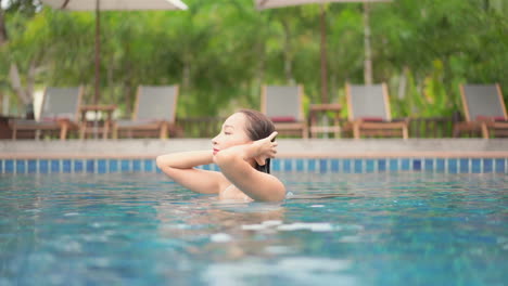 Cámara-Lenta-De-Una-Joven-Asiática-Sexy-Arreglándose-El-Pelo-Mojado-En-La-Piscina-De-Fotograma-Completo