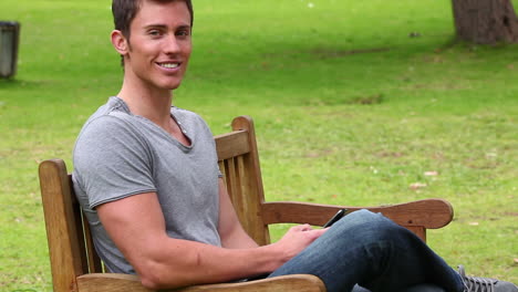 man looking at his phone while sitting with his legs crossed before looking at the camera