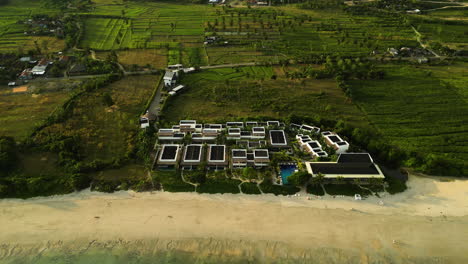 Aerial-top-down-shot-of-sandy-Torok-beach,-with-hotel-resort-and-rural-plantation-on-Lombok-island,-Indonesia---Establishing-shot