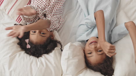 happy sisters looking on camera in bed