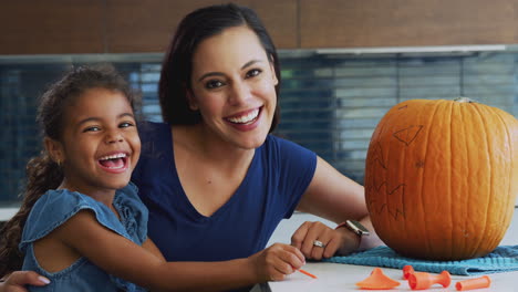 Porträt-Von-Mutter-Und-Tochter,-Die-Zu-Hause-Eine-Halloween-Laterne-Aus-Kürbis-Schnitzen