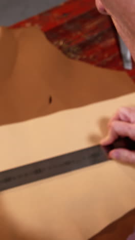 shoemaker marking a piece of leather with pencil