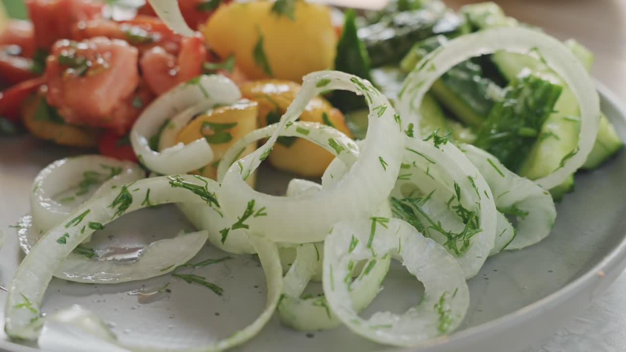 Anéis de cebola servidos. Prato de anéis de cebola temperados com ervas. Fatias crocantes de cebola com molho de ervas no prato. Anéis de cebola assados com molho de ervas servidos com fatias frescas de pepino e tomate.