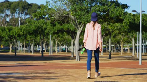 woman with skate board walking in the park 4k