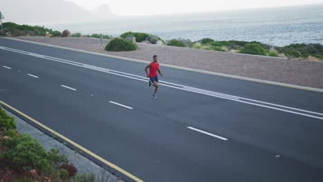 african american man exercising outdoors running on a coastal road