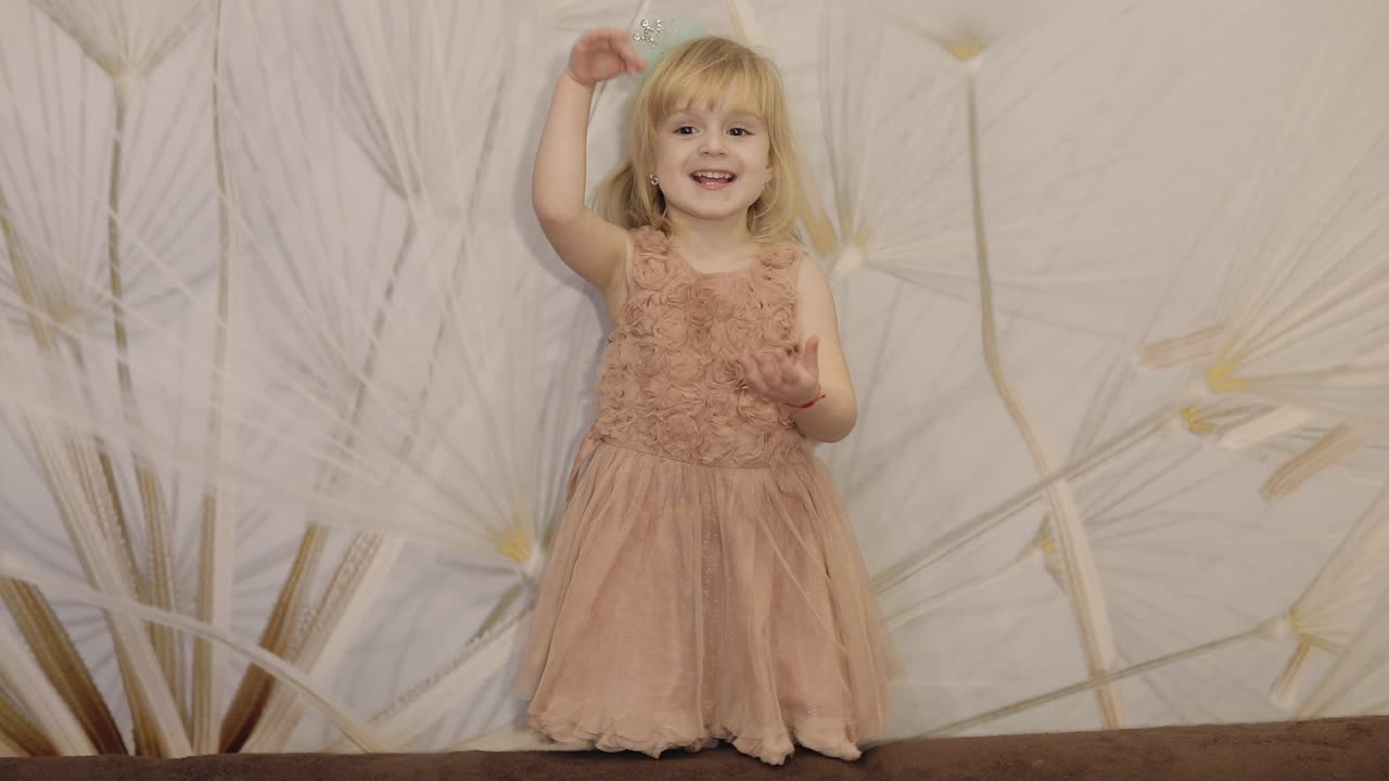 счастливая трехлетняя девочка делает лица и танцует. милая блондинка