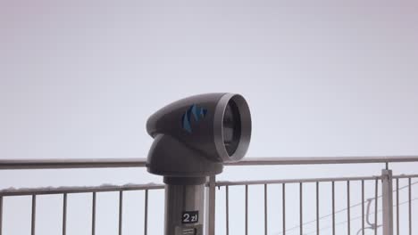 snowy observation deck telescope spinning on pedestal looking out at ski resort cable car scenery