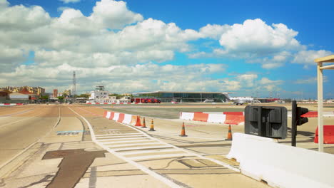 view of an airport runway in gibraltar with a small plane and terminal buildings under a partly cloudy sky