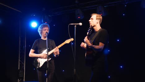 banda de rock de concierto actuando en el escenario con dos guitarras eléctricas cantantes. video musical punk, heavy metal o grupo de rock. banda de instrumentos de cámara lenta de dos hombres