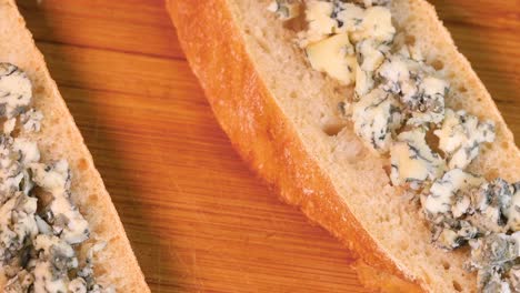 bocadillo de queso azul y pan sobre tablero de madera, girando