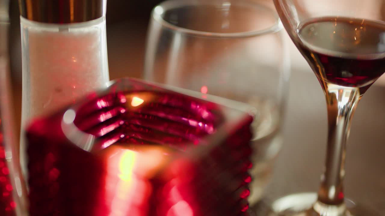 Red wine glass, candle, and glassware on intimate restaurant table with warm, soft lighting