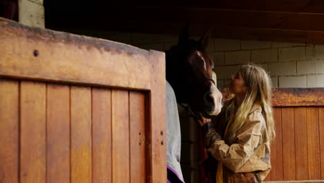 mujer besando a un caballo en el establo 4k