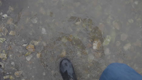 muddy boots walking in shallow water in slow motion