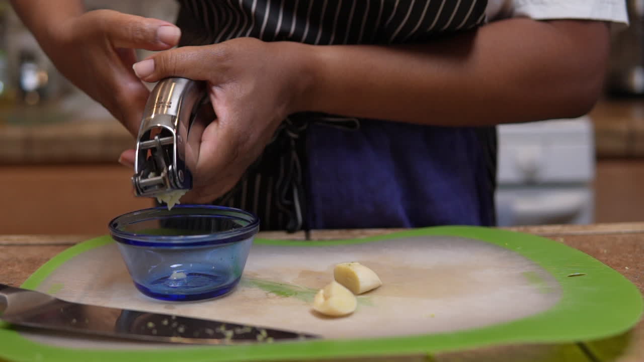 usando una prensa de ajo para picar un diente entero de ajo fresco - cámara lenta