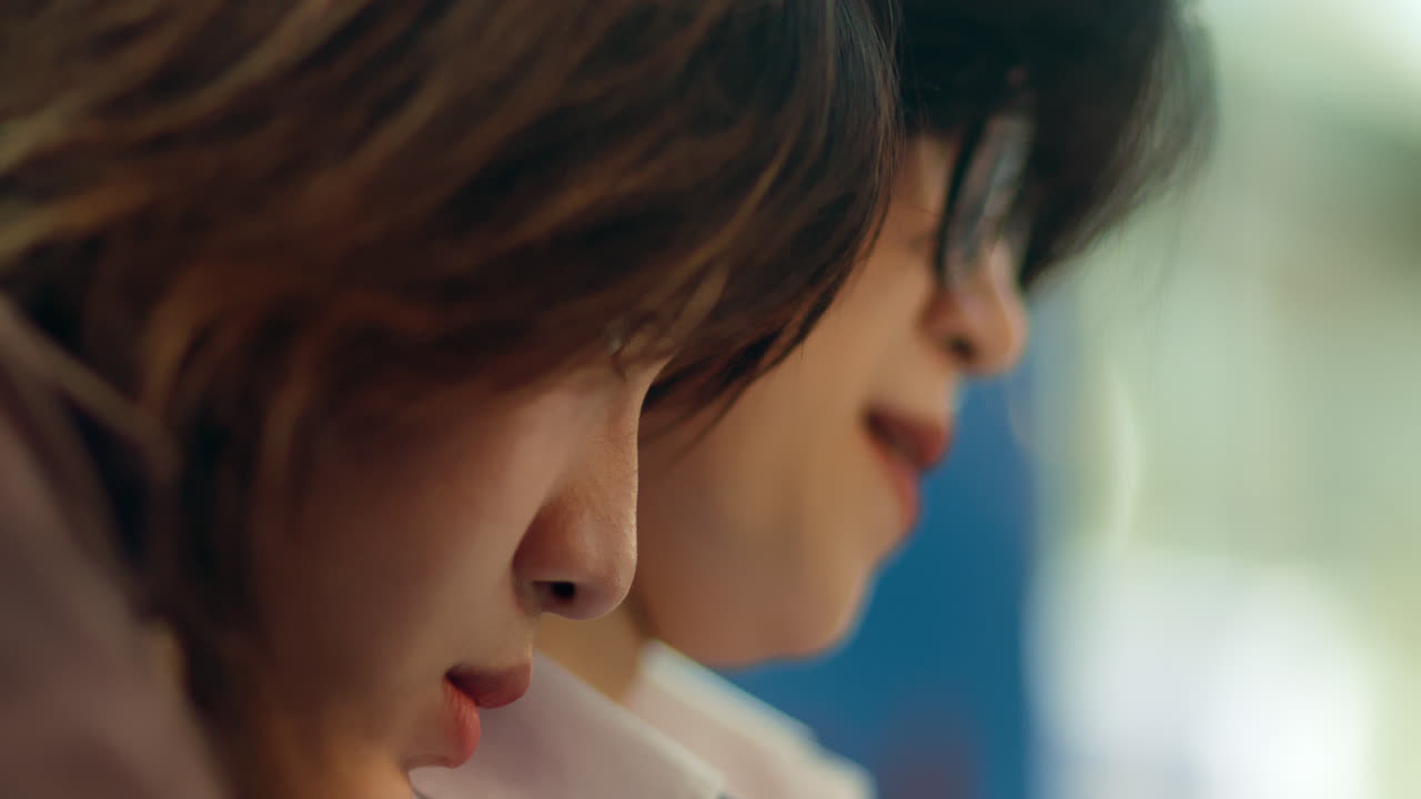 두 명의 미소 짓는 아시아 소녀가 어깨에 머리를 고 웃는 랙 초점