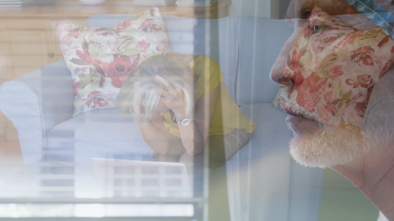 Una donna anziana è preoccupata e seduta su un divano a casa