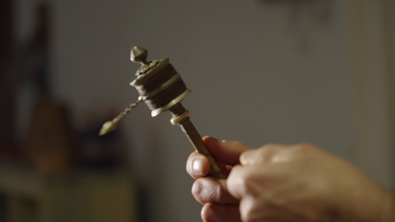 Mano che tiene e fa girare una ruota di preghiera tibetana con grani di preghiera