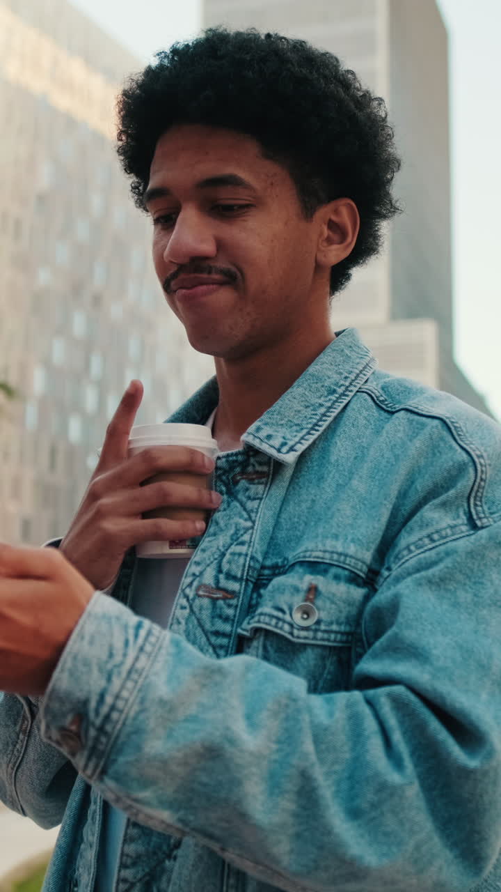 Giovane uomo pensieroso che usa lo smartphone e beve caffè all'aperto